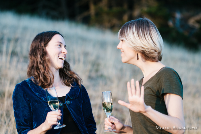 Two young women drinking champaign and talking outdoors