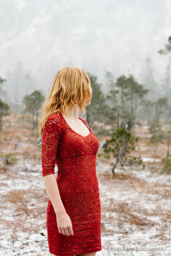 Young woman in red dress looking back from the camera at trees i